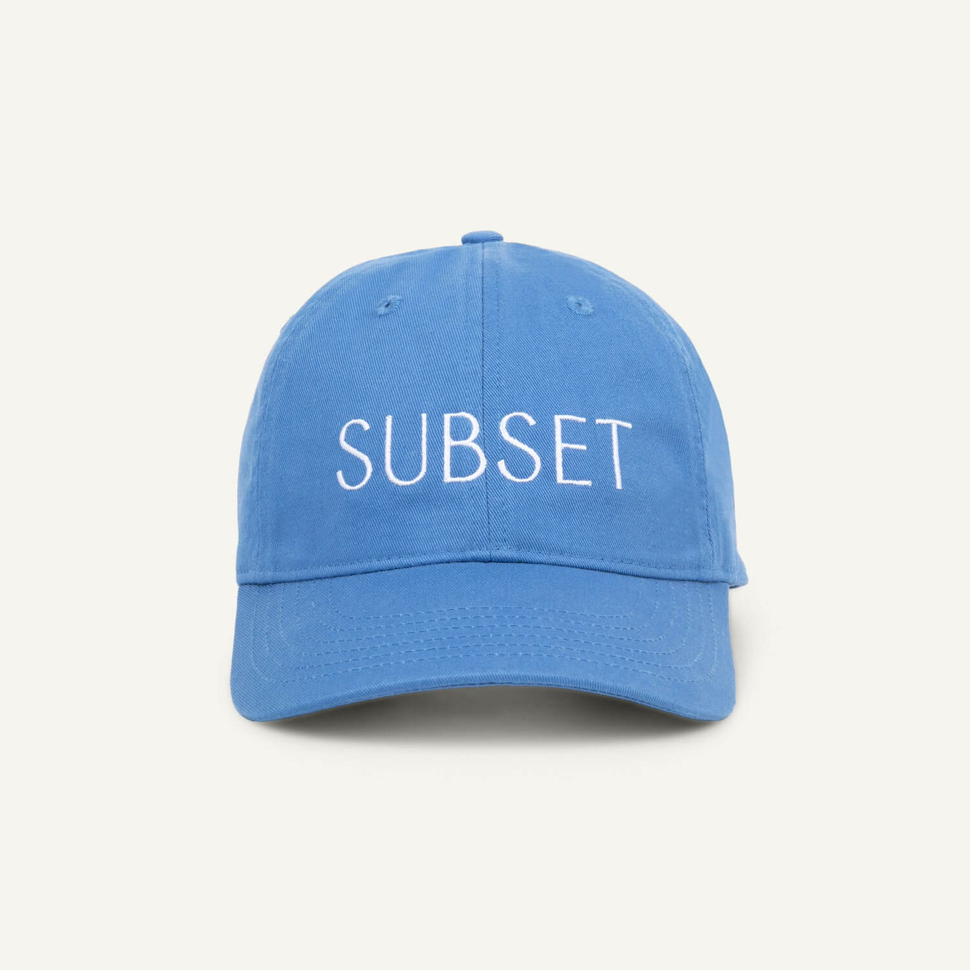 A blue organic cotton baseball cap with the word 'SUBSET' embroidered in white on the front.