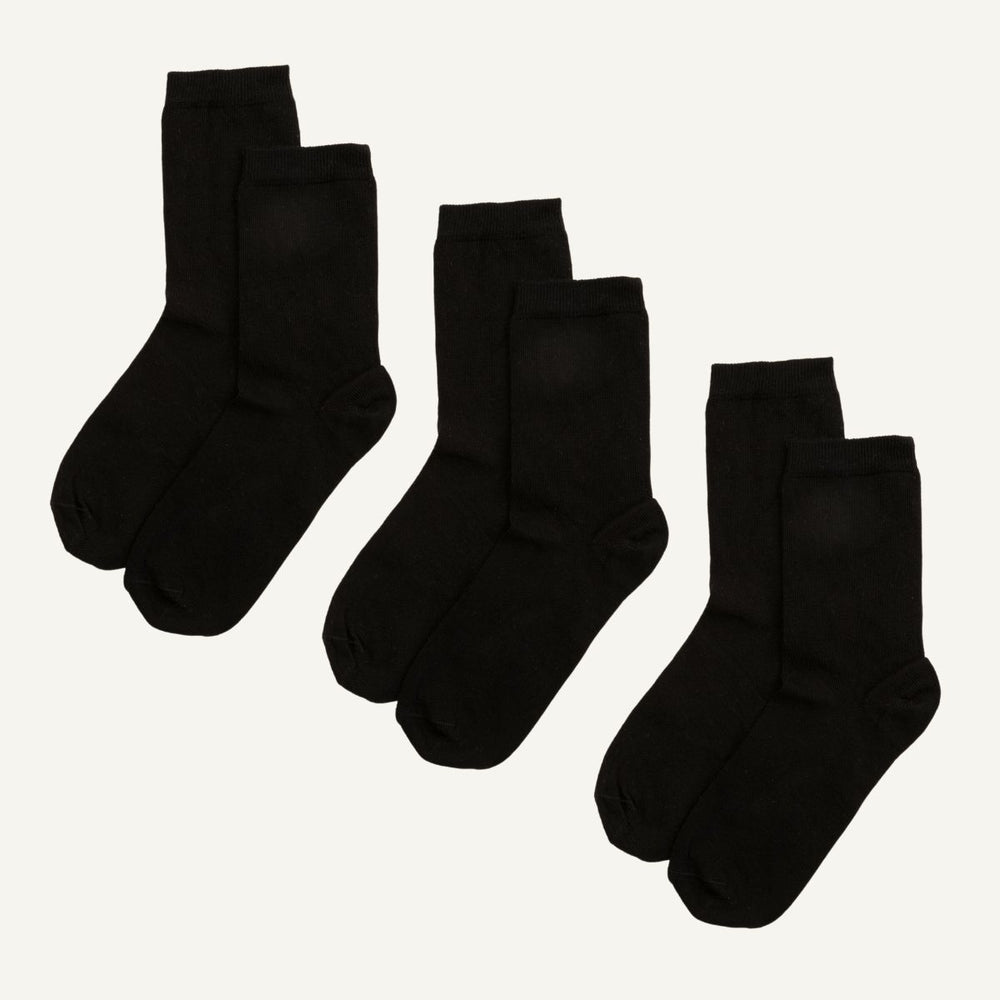 Three pairs of black organic cotton crew socks, designed to sit a few inches above the ankle.